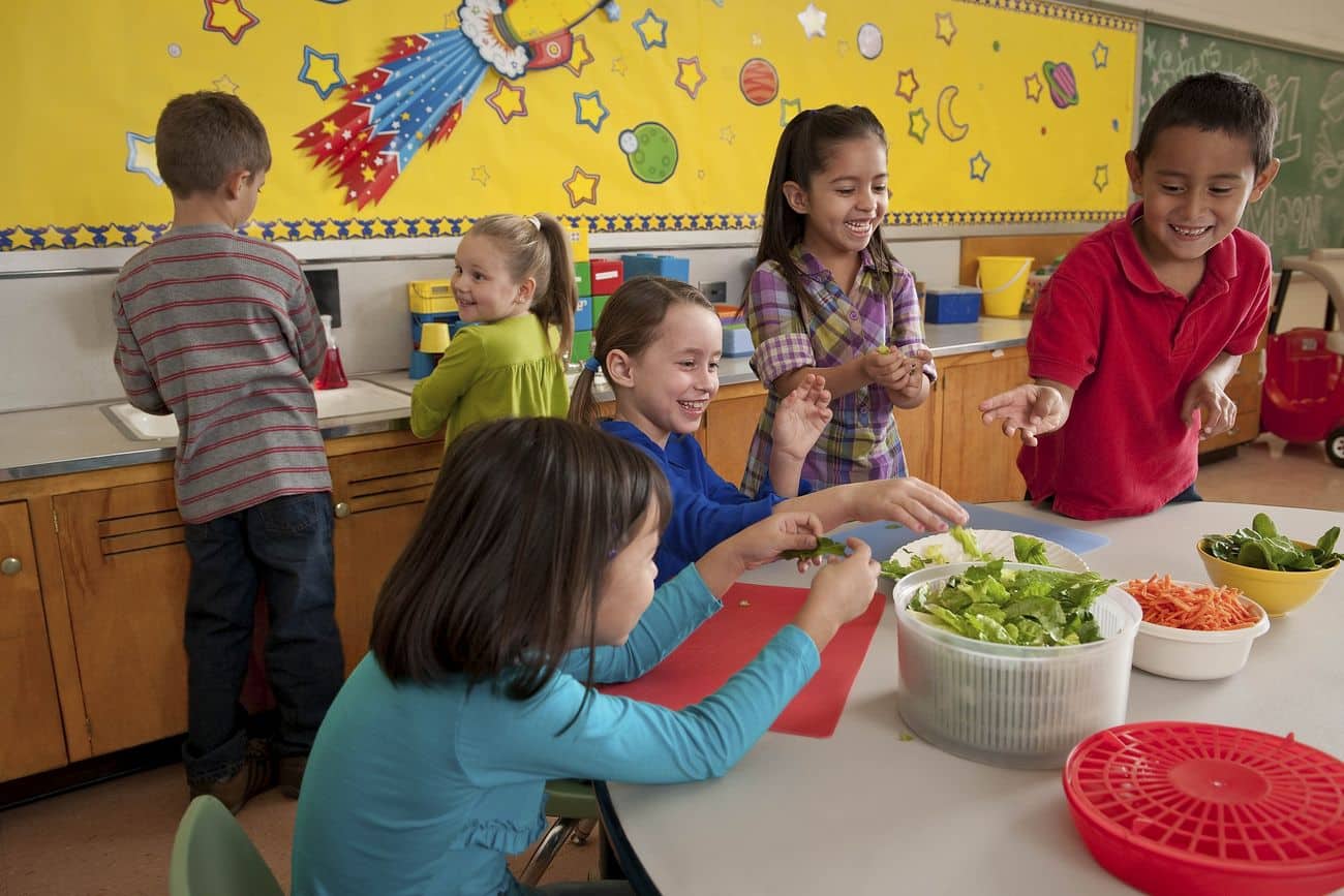 Schoolchildren making a salad together while learning to cook