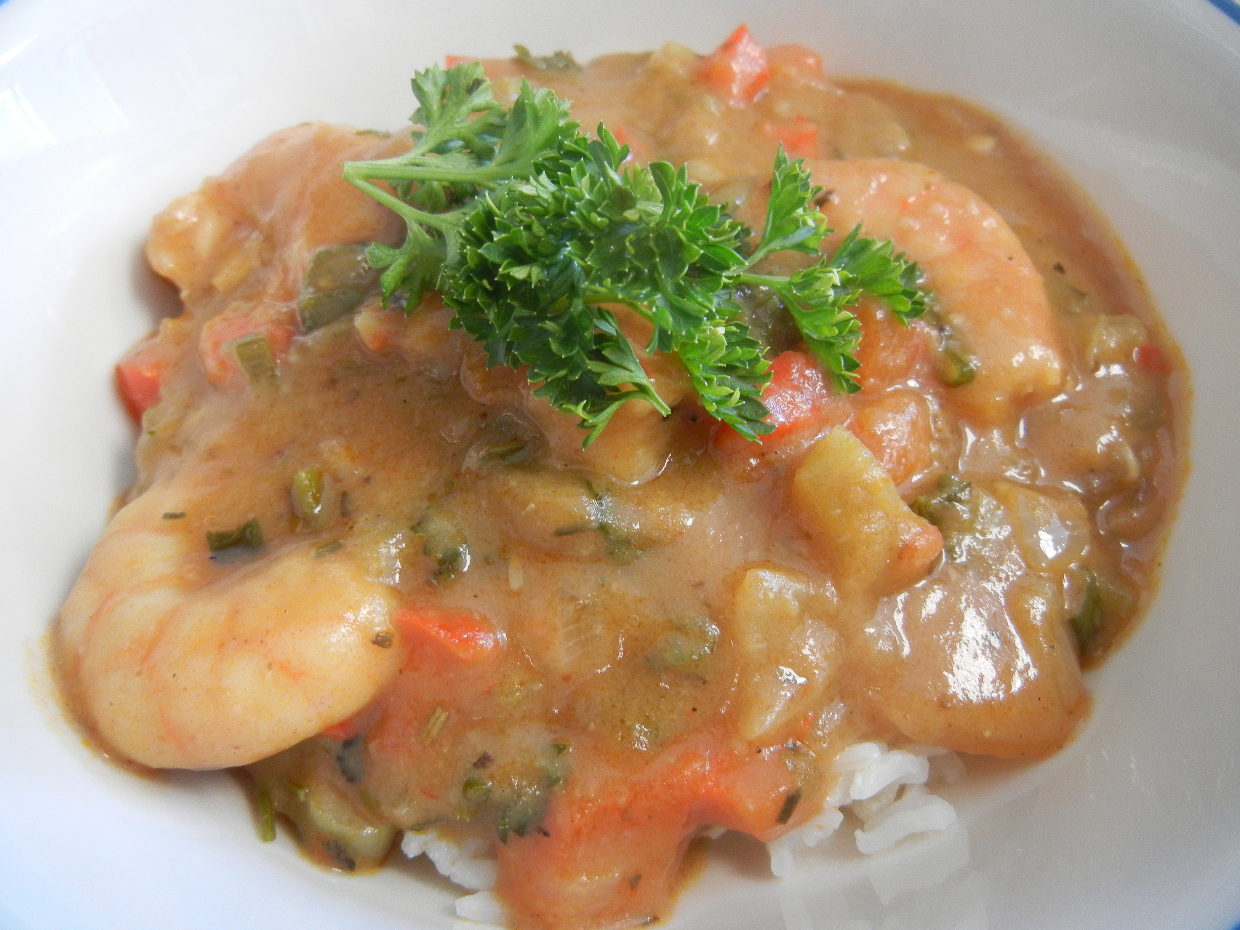 Shrimp gumbo with rice on a white background with parsley for garnish