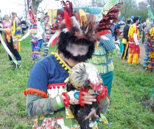 Image of a young person in traditional Mardi Gras attire holding a chicken