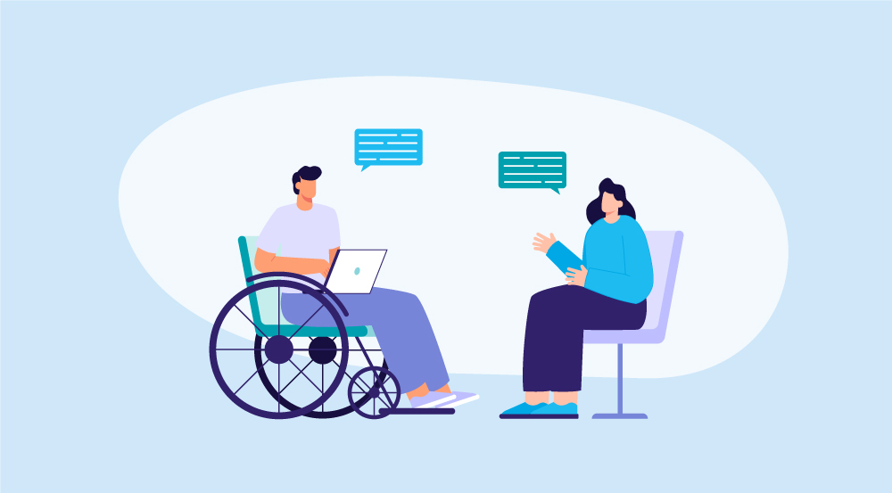 Two colleagues collaborating in a workplace; one is seated in a wheelchair using a laptop while another stands beside them, s