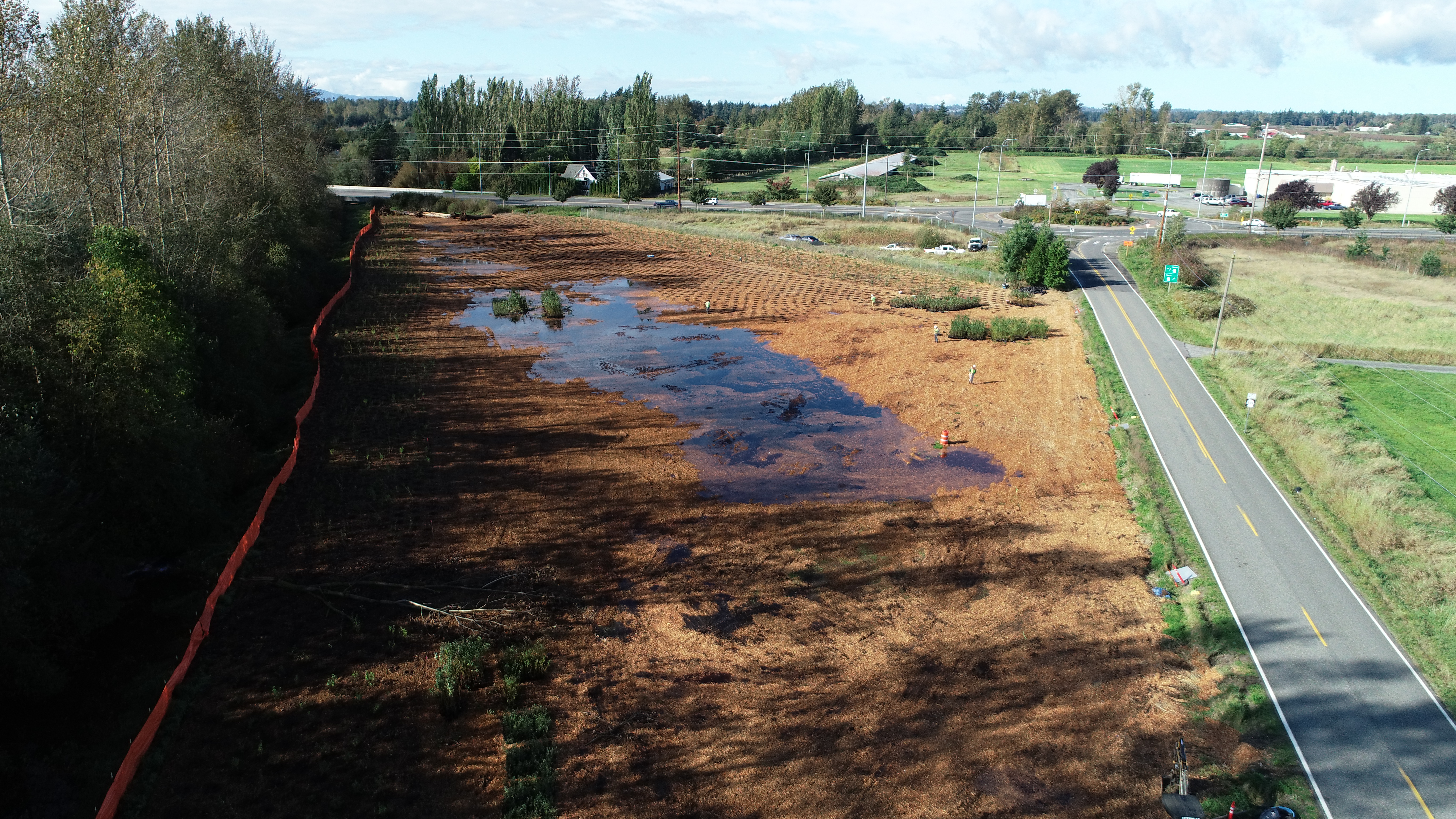 An aerial photo of a portion of land being returned to floodplain next to a road. 