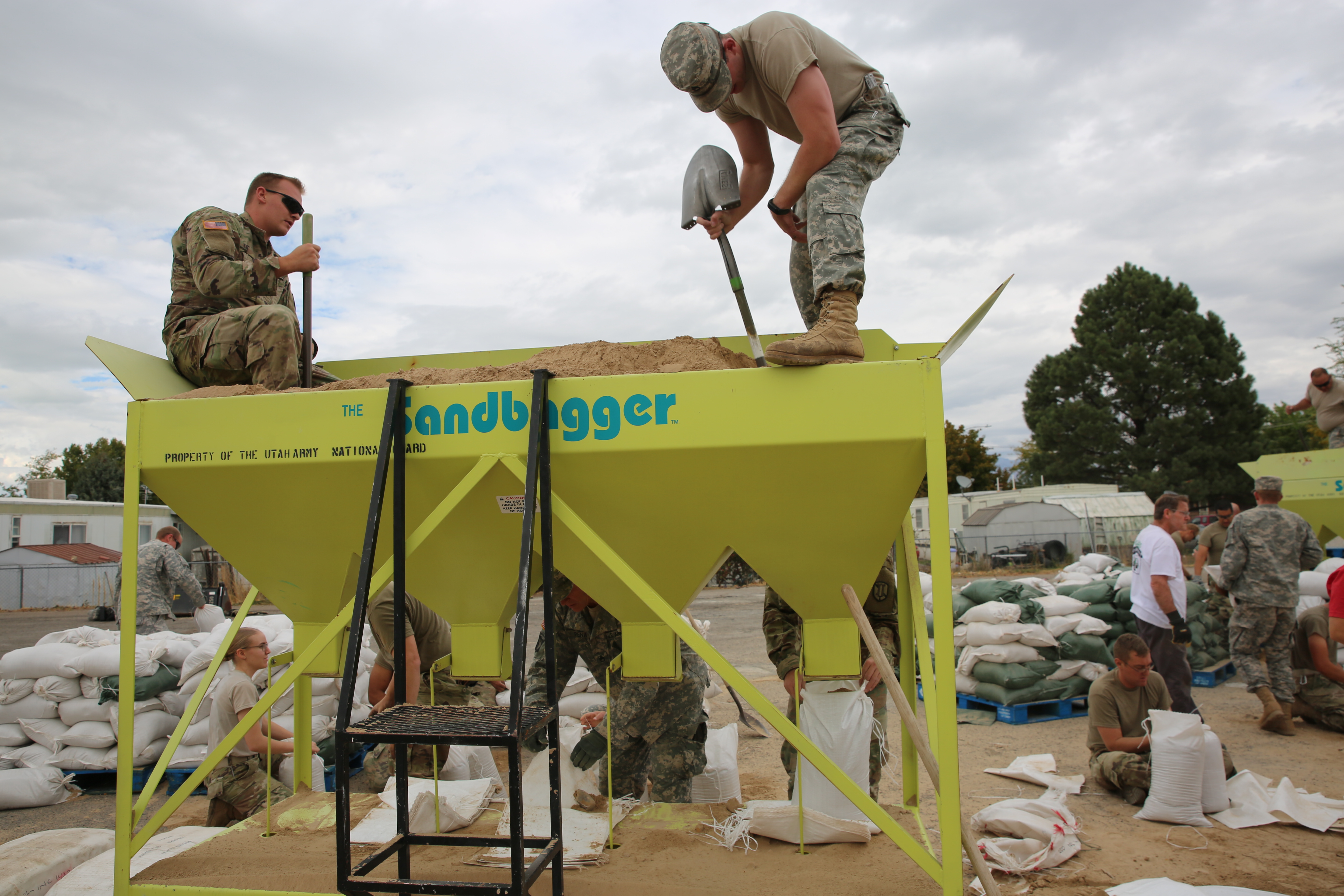 Guardsmen standing on top of sandbagging device