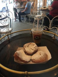 A plate of beignets - sugared donuts - and an iced coffee on a table in Cafe Dumond in New Orleans. 