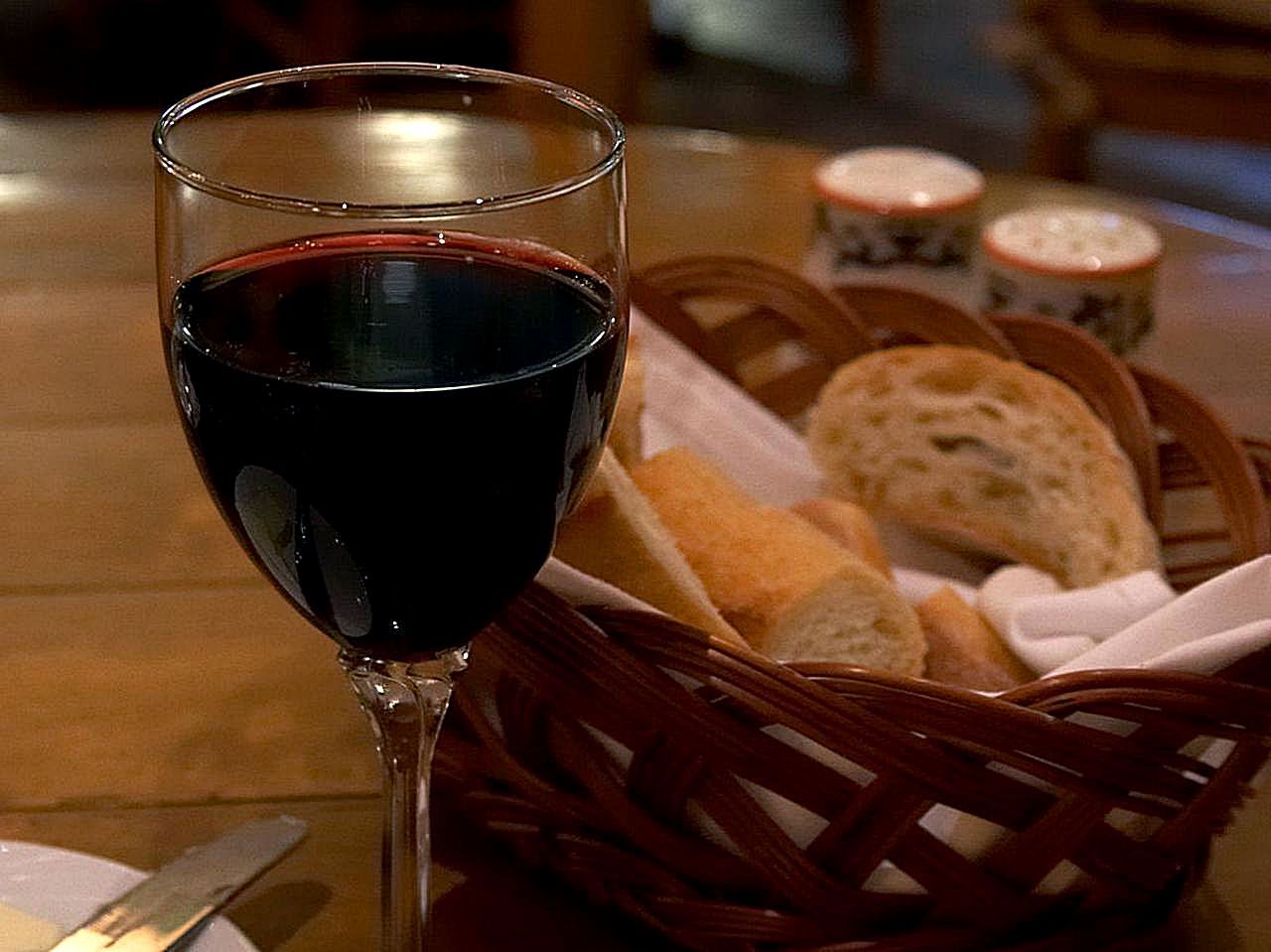 Red wine and a basket of bread on a wooden table