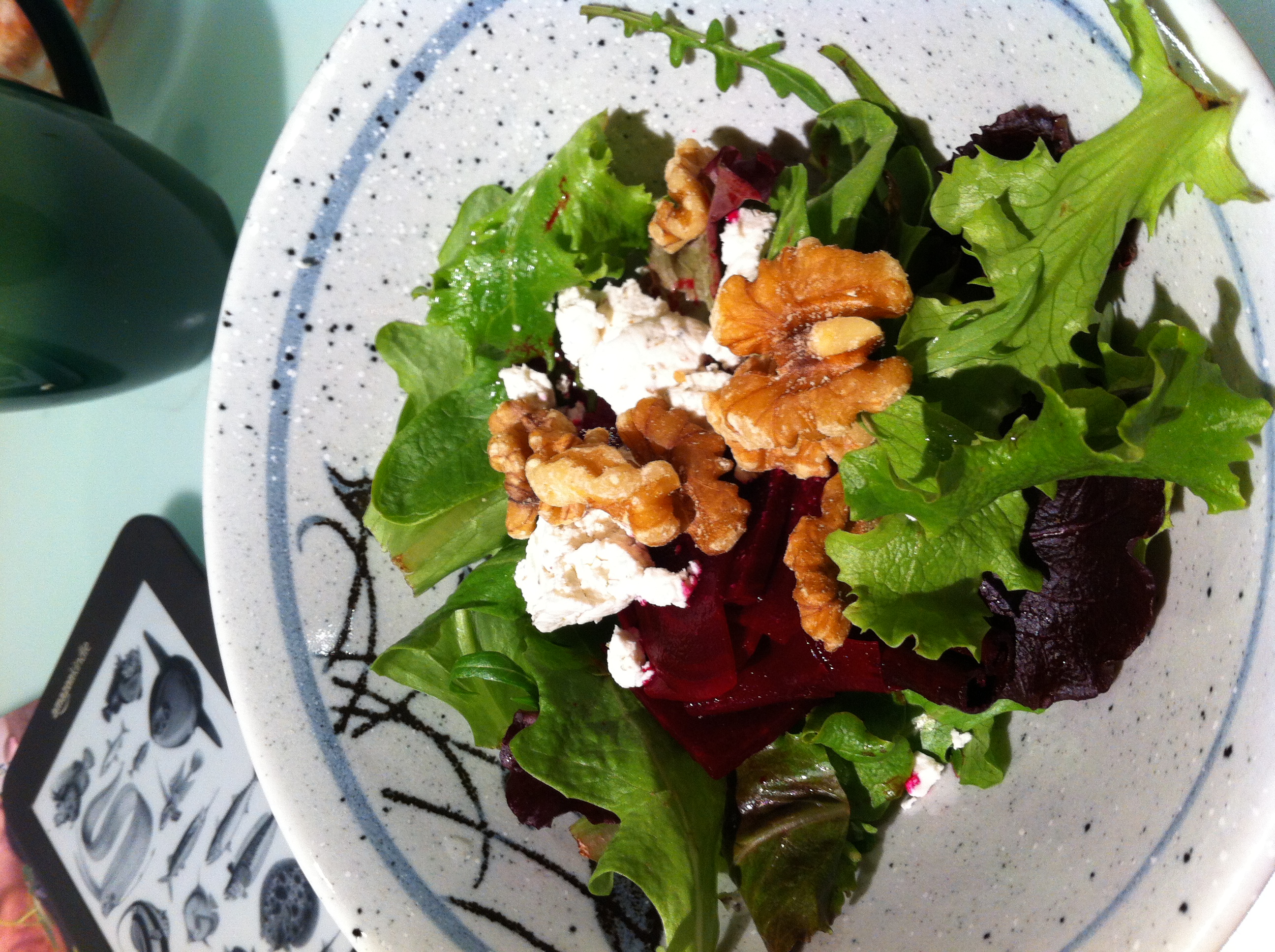 Salad with walnuts and goat cheese in a speckled ceramic bowl