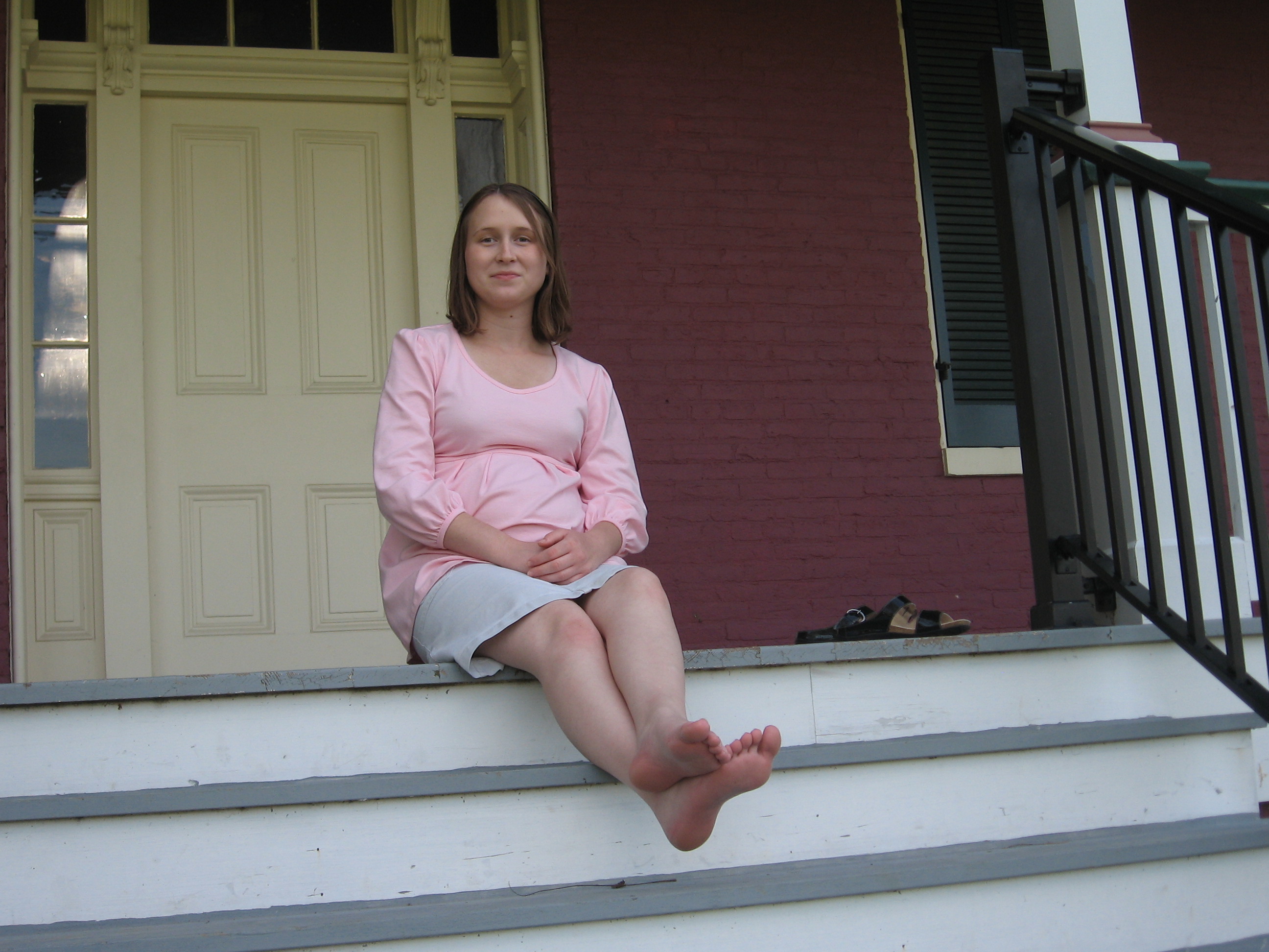 Pregnant woman sitting barefoot on porch steps